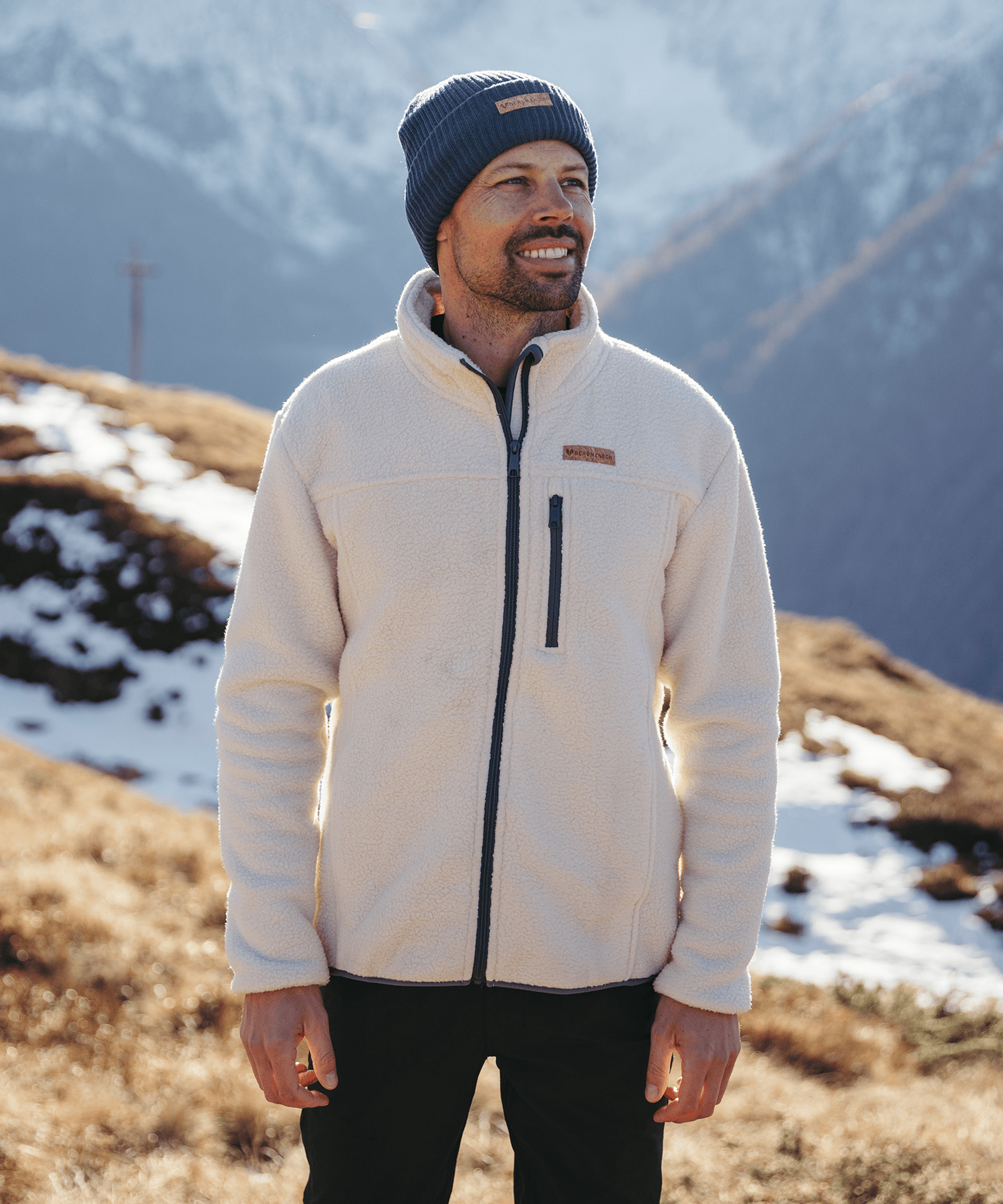 Model trägt die BERGMENSCH Herren Sherpa Fleece Jacke in der Farbe Whitecap Grey und die Cozy Fleece Beanie in der Farbe Midnight Navy