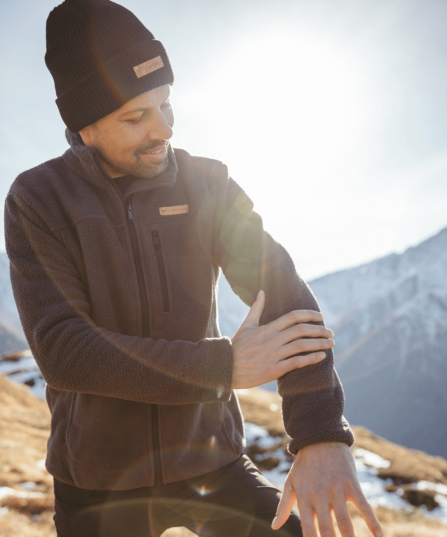 Model trägt die BERGMENSCH Herren Sherpa Fleece Jacke in der Farbe Ink Black und die Cozy Fleece Beanie in der Farbe Black