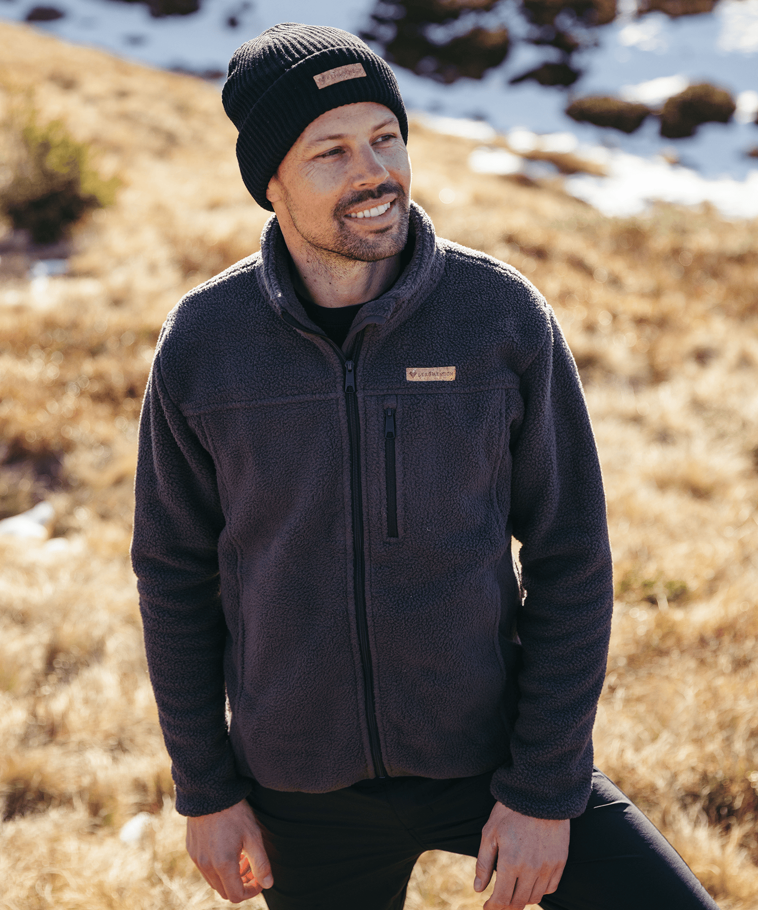 Model trägt die BERGMENSCH Herren Sherpa Fleece Jacke in der Farbe Ink Black und die Cozy Fleece Beanie in der Farbe Black