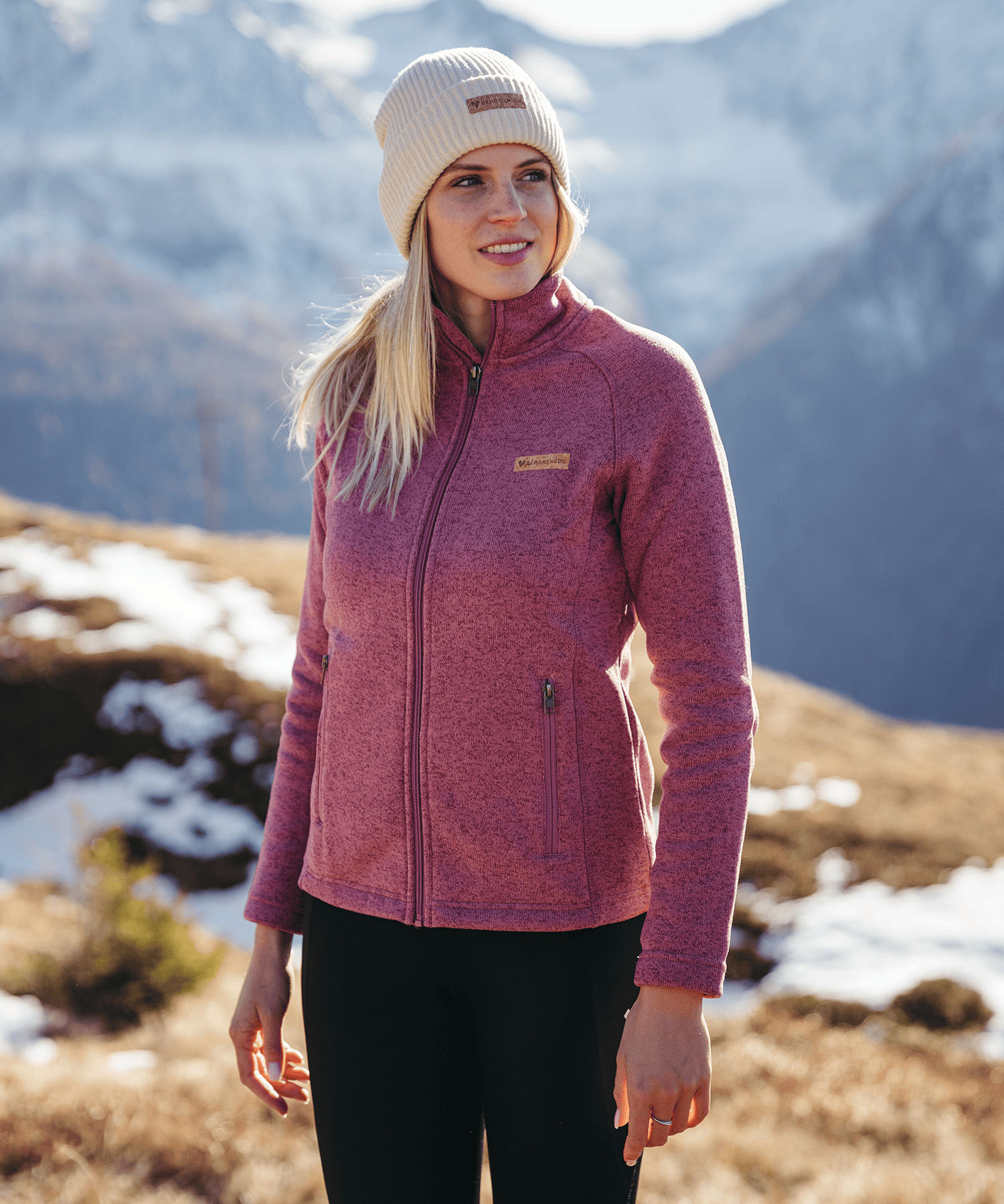 Model trägt die BERGMENSCH Damen Strickfleece Jacke in Hibiscus in den Bergen