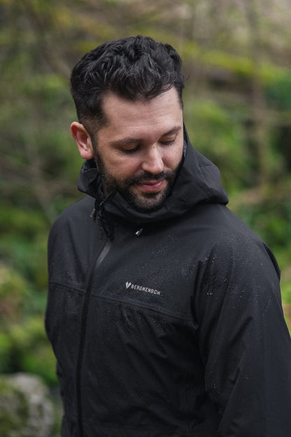 Model trägt BERGMENSCH Herren 3L Hardshell Regenjacke in der Farbe Black