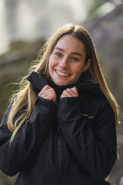 Model trägt BERGMENSCH Damen 3L Hardshell Regenjacke in der Farbe Black